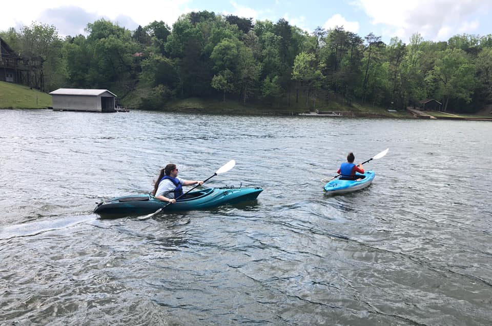 two students on kayaks in a lake